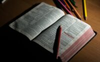 pink pencil on open bible page and pink